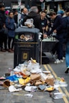 person standing beside garbage bin