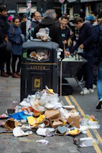 A crowded urban street with people enjoying life contrasted by polluted rivers and trash.