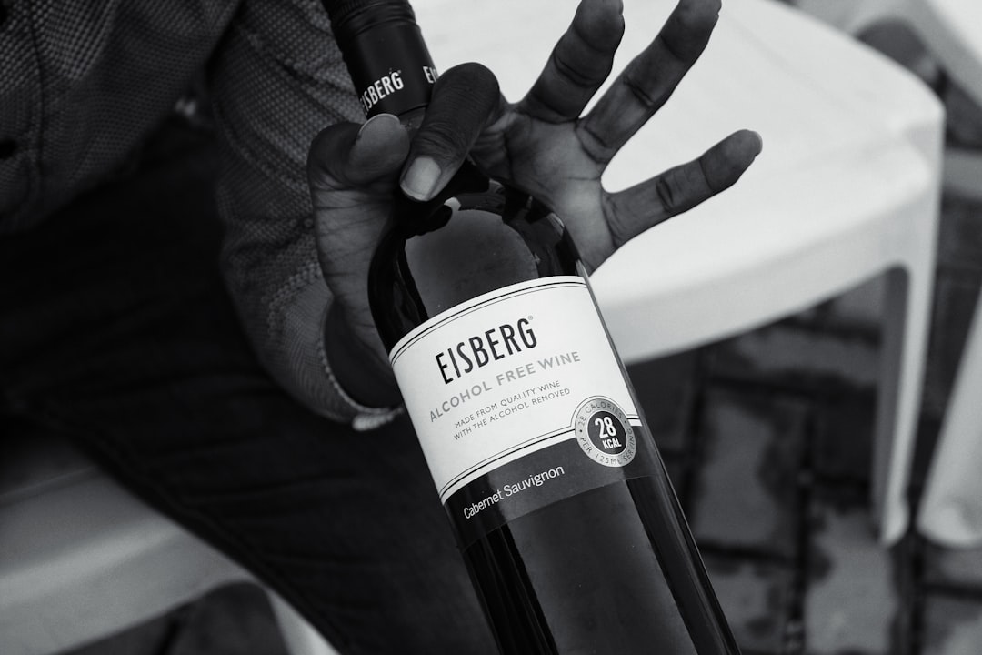 grayscale photo of person holding Eisberg Alcohol Free wine boottle