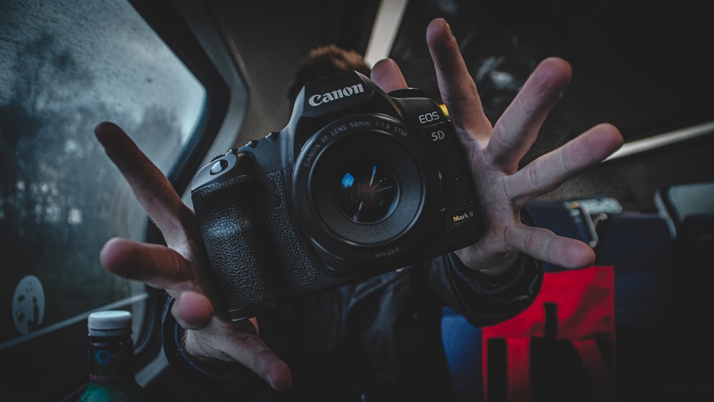 person holding black Canon DSLR camera