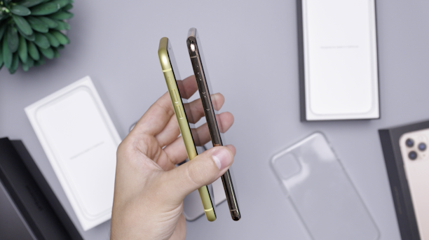 Hands holding two different smartphones side by side against a neutral background.