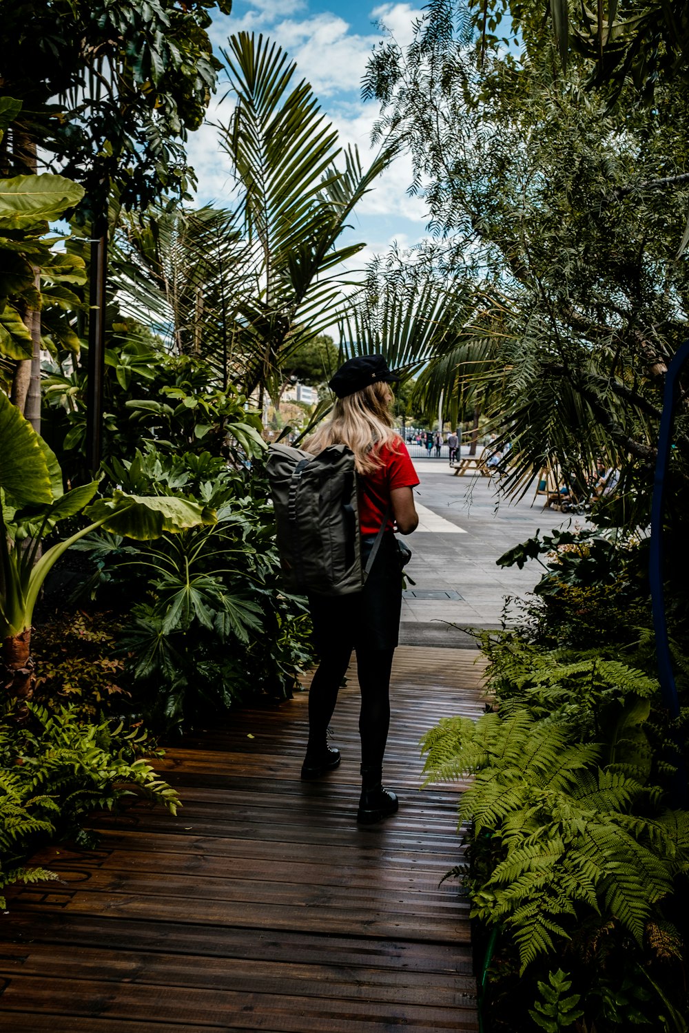 woman standing on footbridge surrounded by plants