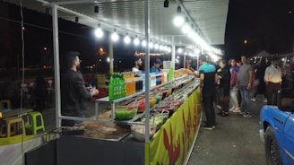 Photo of a colorful food stall inside a busy shopping center with various local dishes displayed.