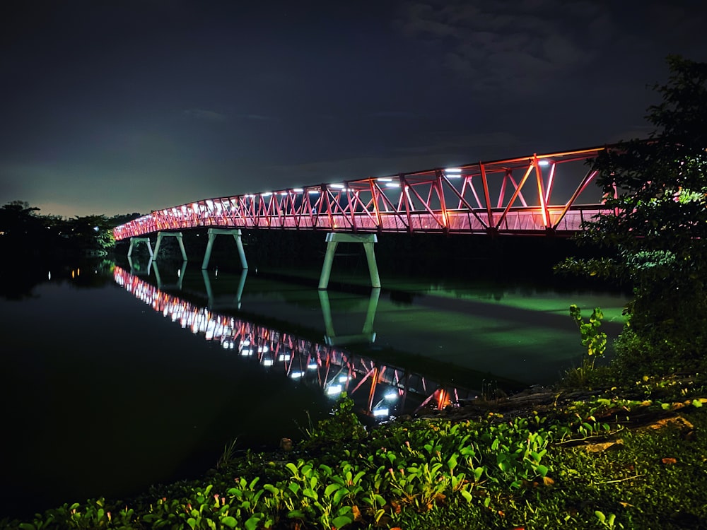 a red bridge over a river at night