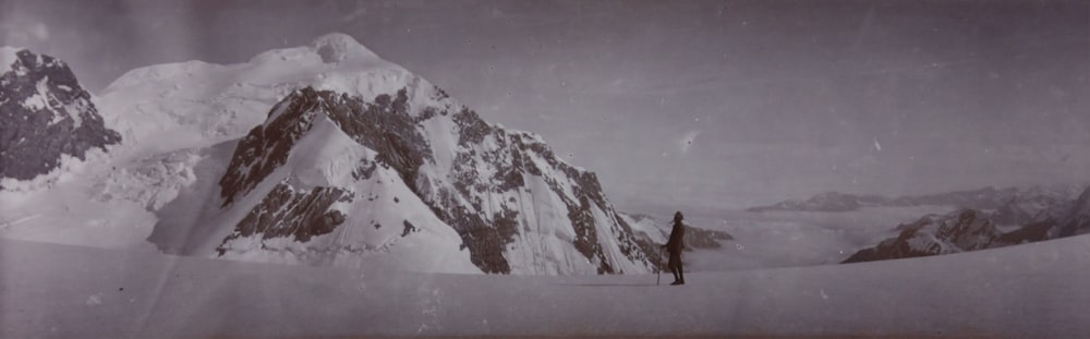 Un uomo in piedi sulla cima di una montagna coperta di neve