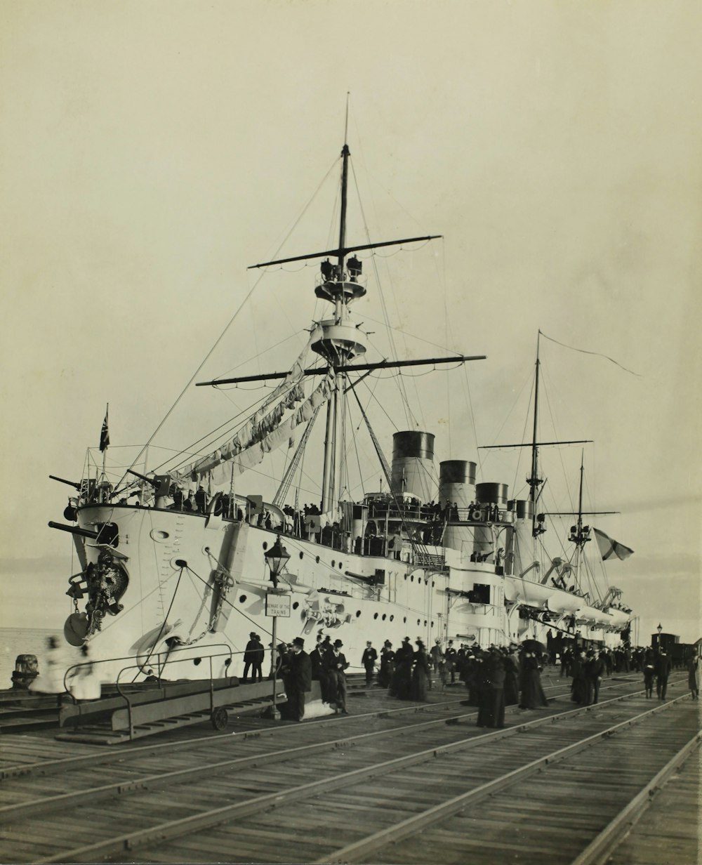 grayscale photo of ship on pier