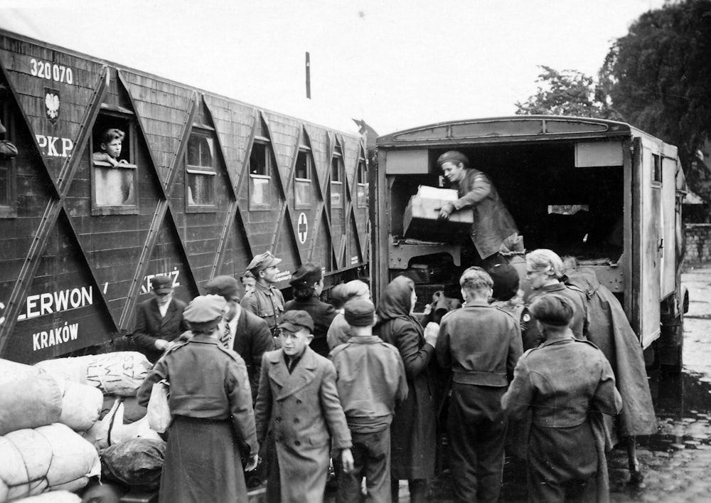 Photographie en niveaux de gris d’hommes faisant la queue à l’arrière d’un camion