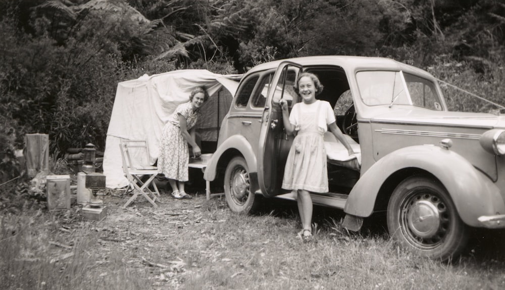 Foto en escala de grises de una chica al lado del coche