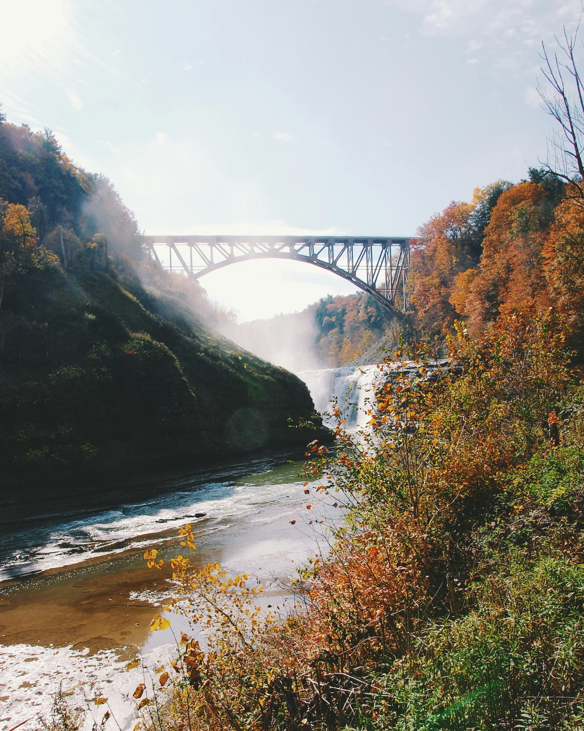Beautiful Pennsylvania scenery with misty waterfall under a bridge with fall colors