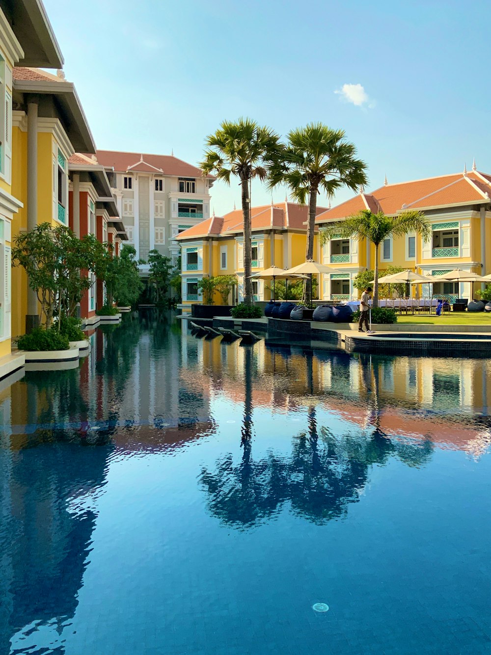 reflection of houses and trees on water under blue sky