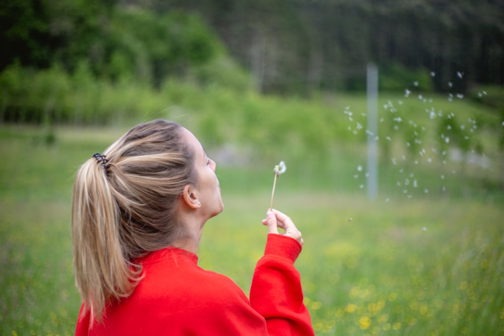 flaches Fokusfoto einer Frau im roten langärmeligen Hemd, die Seifenblasen bläst