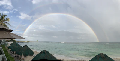 Sunset view over the turquoise coastline with a rainbow arching above.