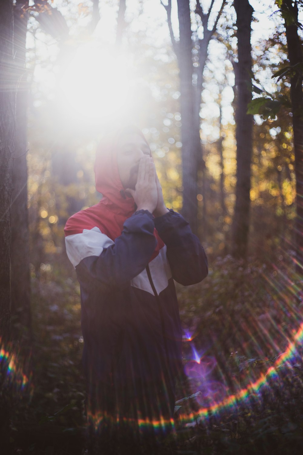 man standing in forest with arms on head