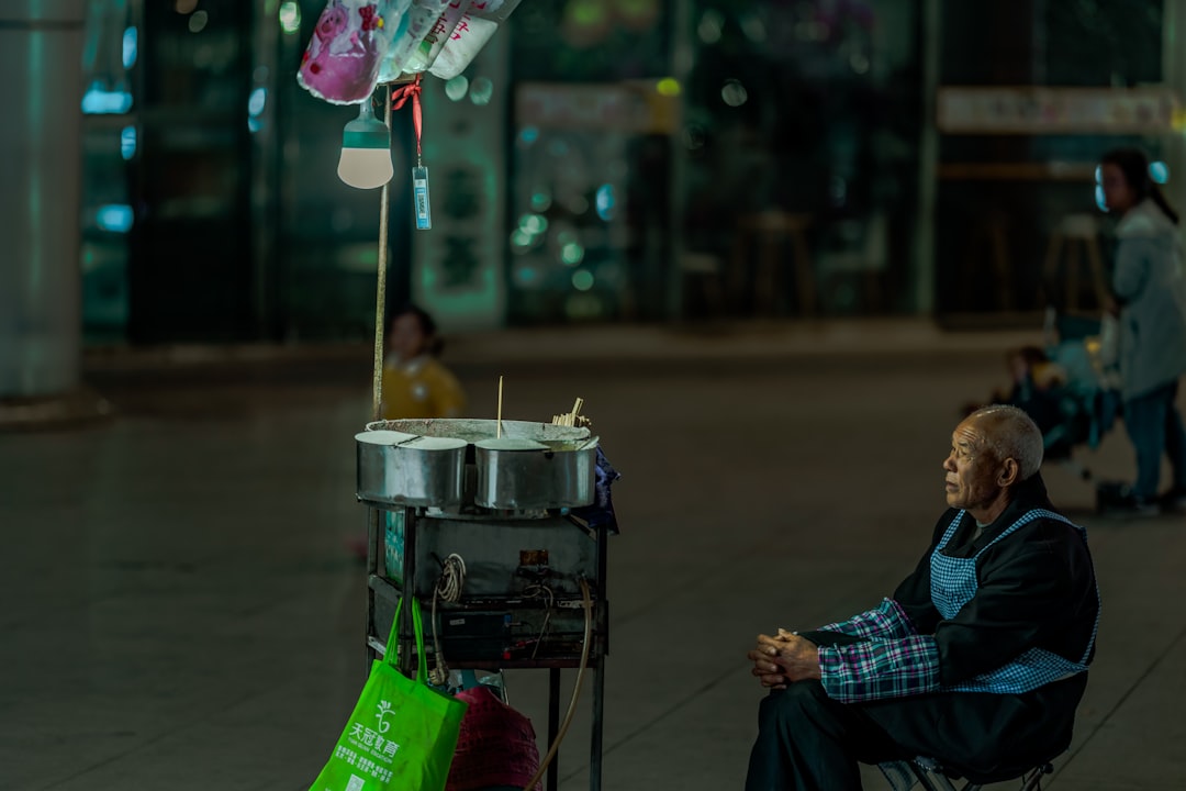 man sitting in front of street food stall