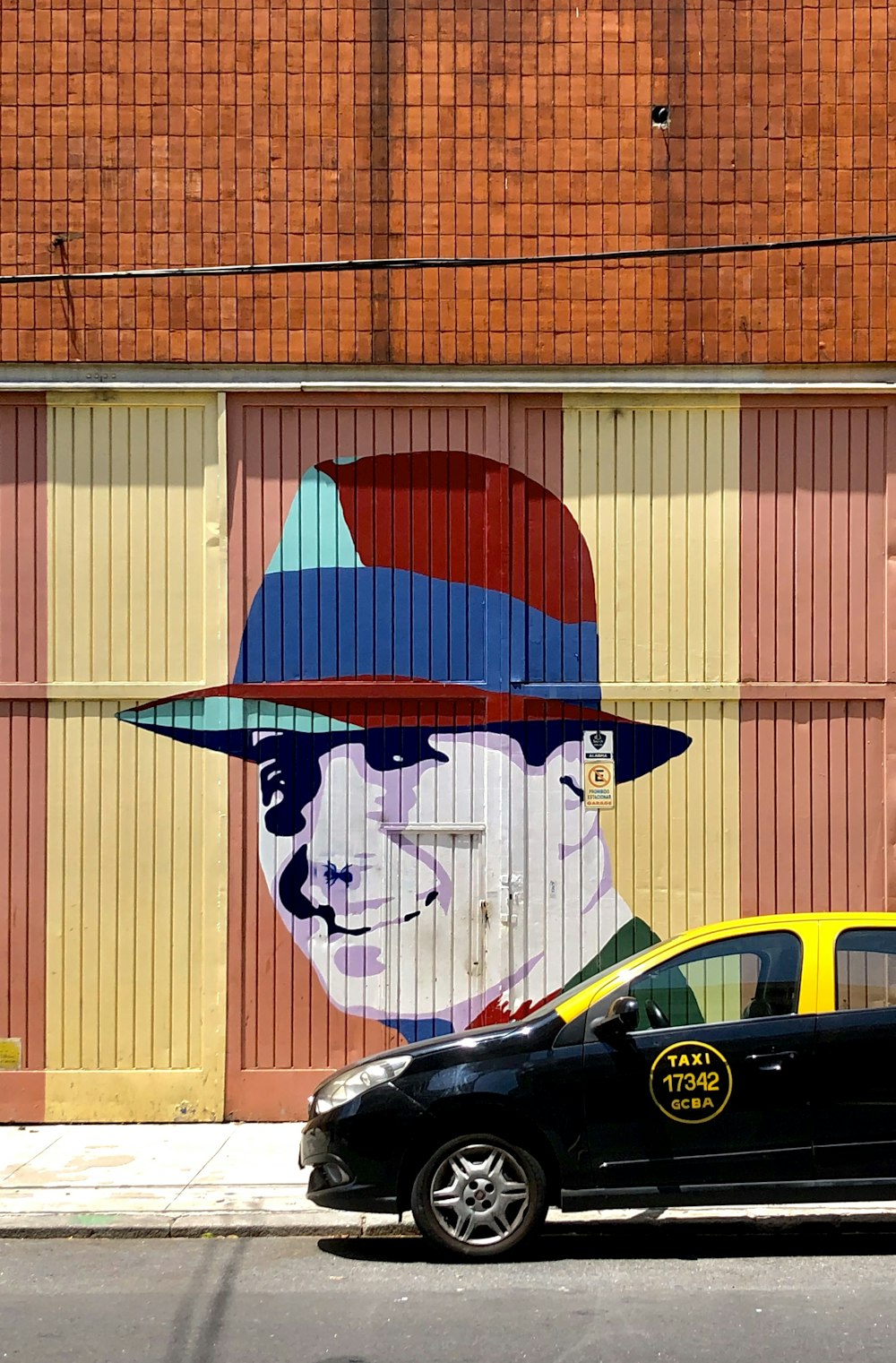 black and yellow vehicle parked near wall with human face painting during daytime