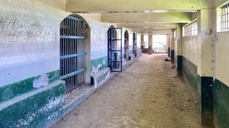 Close-up of a caretaker's boots walking along a stable aisle with hay scattered.