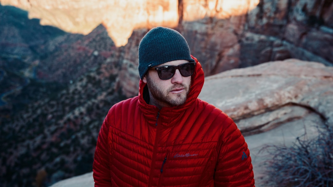 shallow focus photo of man in red full-zip hoodie wearing black sunglasses