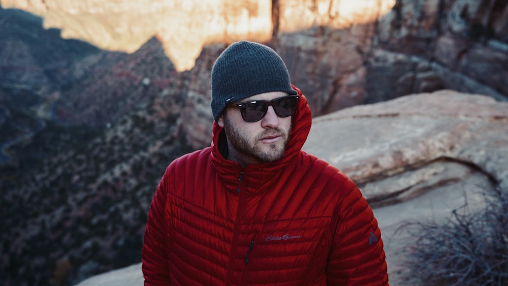 shallow focus photo of man in red full-zip hoodie wearing black sunglasses