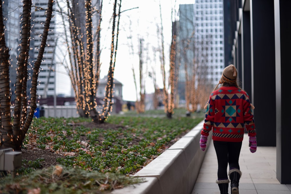 woman walking beside bare trees during daytime