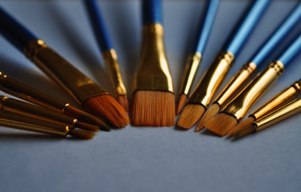 macro photography of blue and gold makeup brush set
