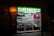 A brightly lit convenience store with a prominent green sign reading 'Supermercat Botiga de Conveniencia.' The store window displays an array of merchandise, including plates, souvenirs, and items featuring the FC Barcelona logo.
