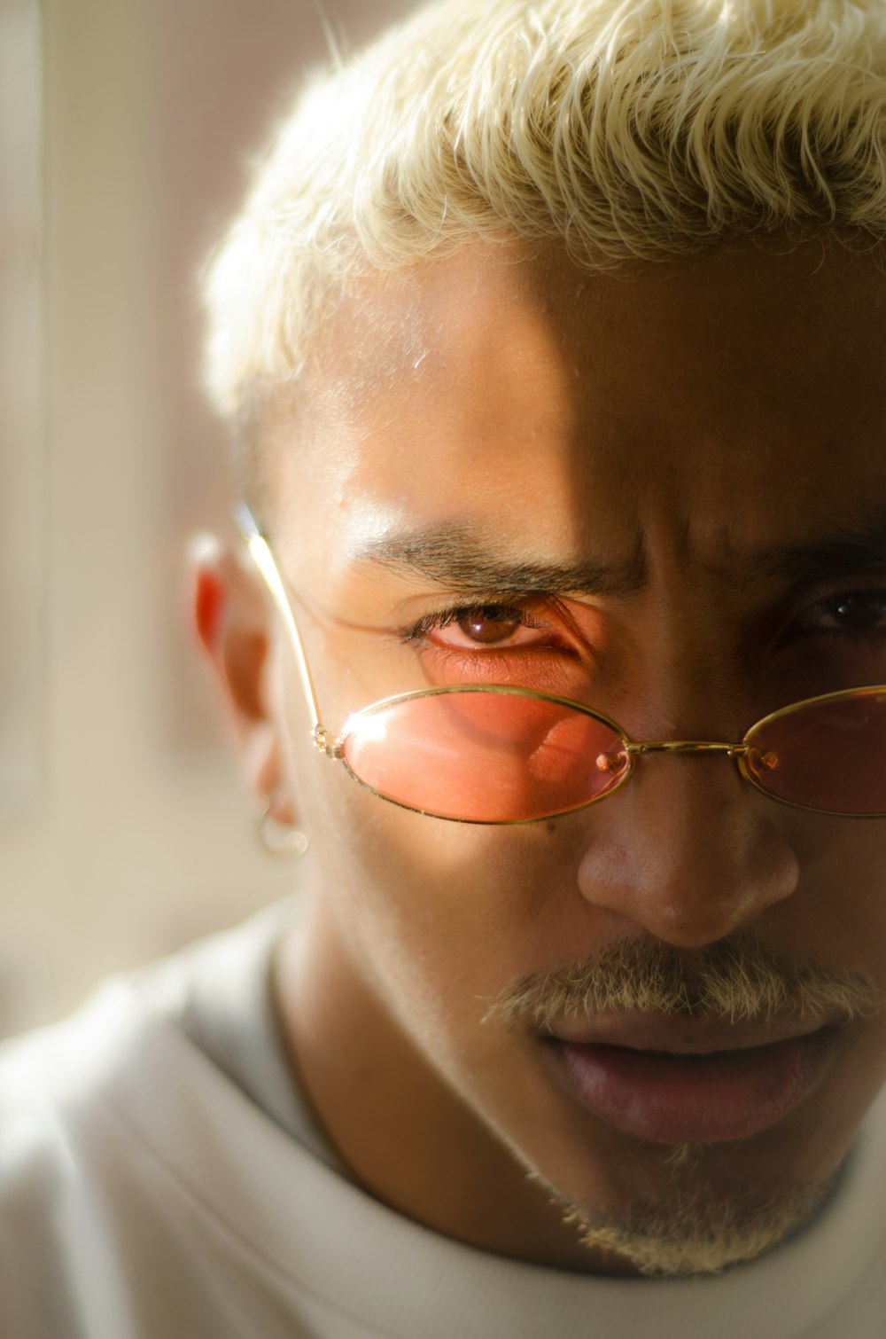 shallow focus photo of man in white crew-neck shirt wearing red sunglasses