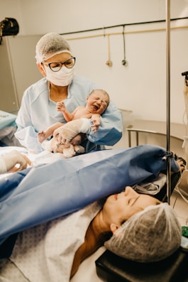 a doctor showing a baby to its mother after c-section