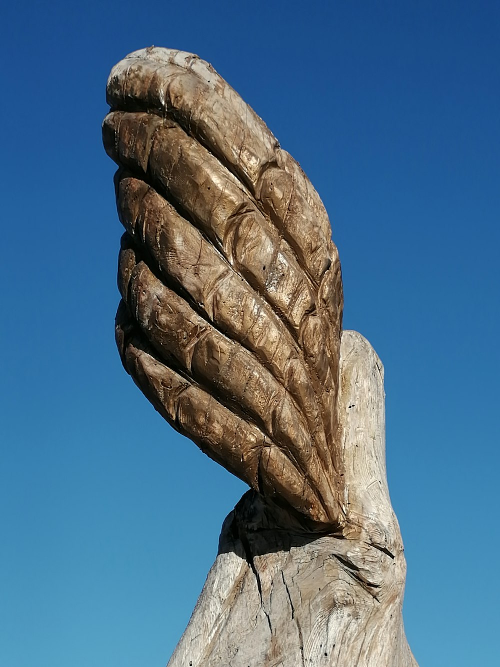 a wooden sculpture of a hand holding a piece of wood