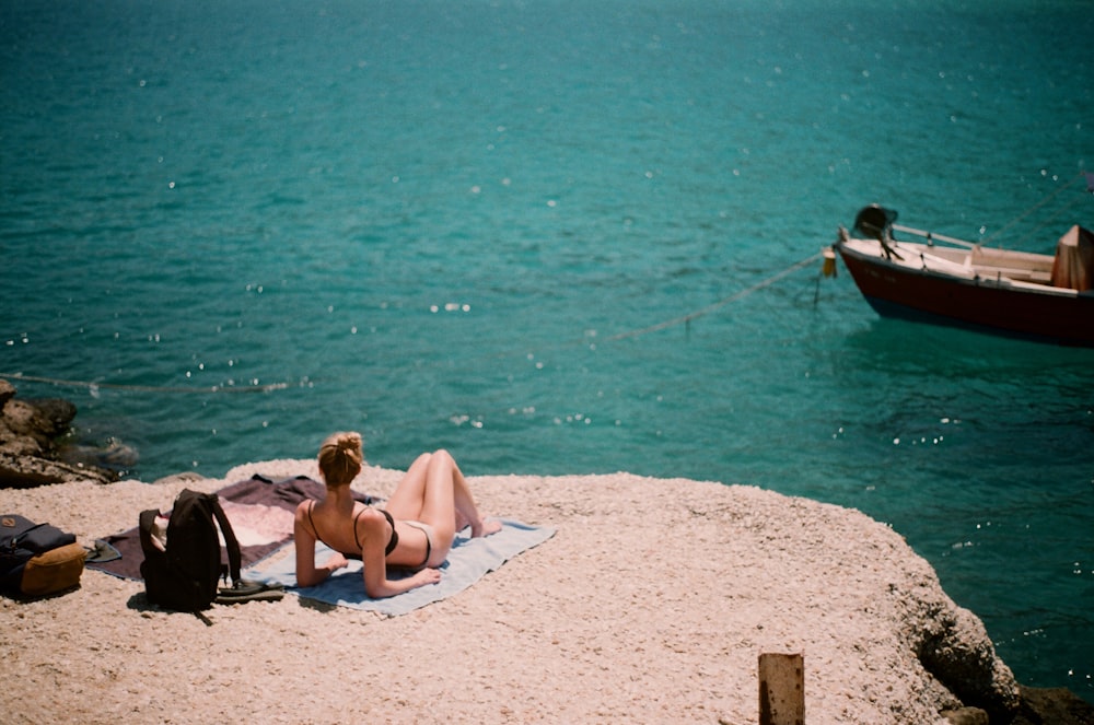 woman lying on cliff overlooking body of water