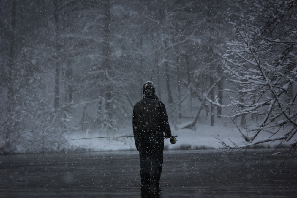 grayscale photography of man fishing while snowing