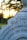 A close-up of an old, weathered tombstone with engraved text commemorating Alexander and his daughter Jane Forbes. The background features blurred trees and a golden sunset sky, creating a serene and contemplative atmosphere.