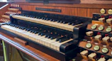 An old church organ with polished wooden pipes and keys.