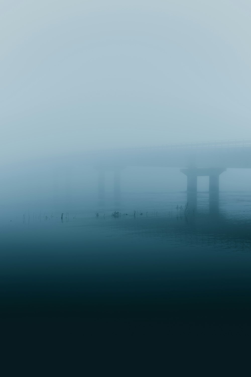 a bridge in a foggy sky over a body of water