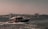 A boat is traveling through the water with seagulls flying overhead. In the background, a cityscape features several mosques with domes and minarets, under a clear sky.