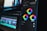 A close-up view of a digital video editing software interface, focusing on color grading tools. Three color wheels labeled Midtones, Shadows, and Highlights are prominent, with sliders for adjusting color balance. The background shows a blurred timeline with video and audio tracks, indicating an ongoing editing process.