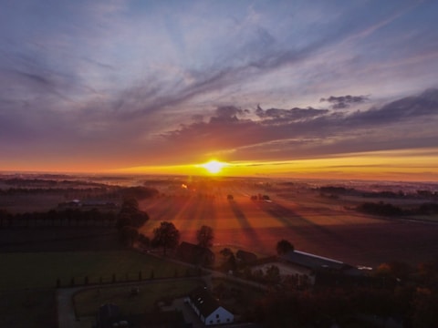 Solar farm in a rural landscape with sunrise casting warm light over the panels.