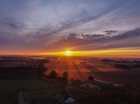 A warm sunrise breaking through dark clouds over a quiet village.
