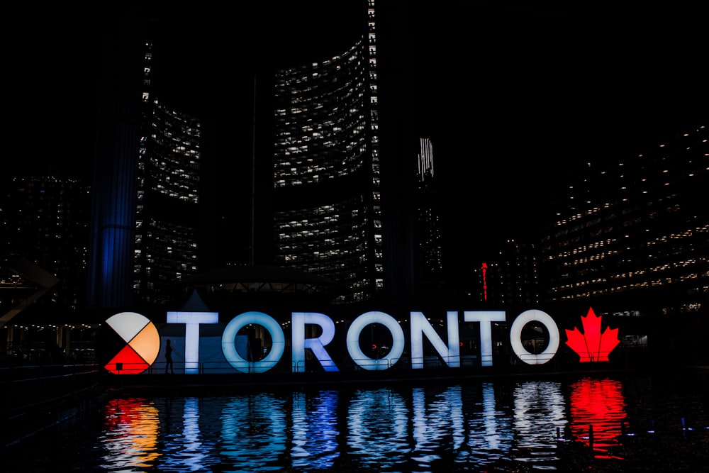 Toronto sign reflecting on body of water at night