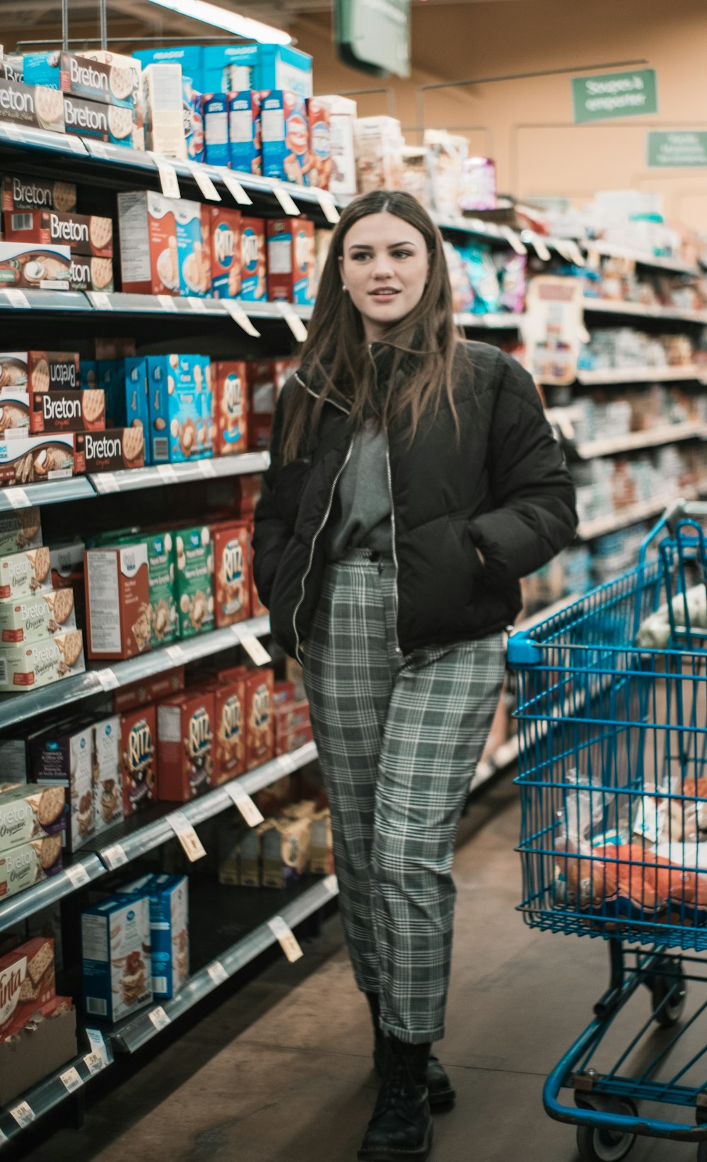 woman standing near shopping cart and groceries inside warehouse
