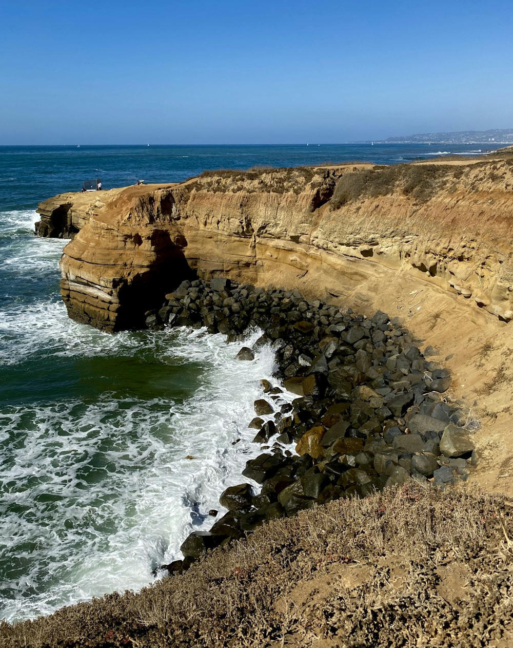 rocky cliff facing ocean under blue sky