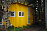 yellow mobile home surrounded by green trees