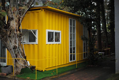yellow mobile home surrounded by green trees