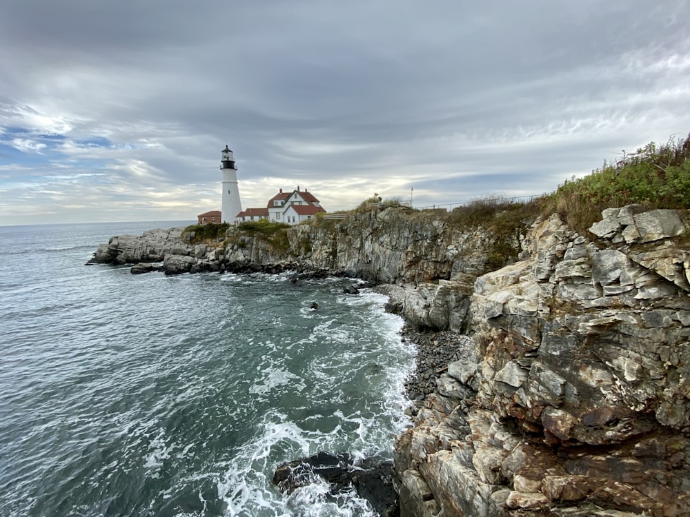 white lighthouse on cliff near body of water