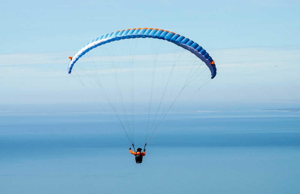 pessoa que cai de paraquedas sob o céu azul