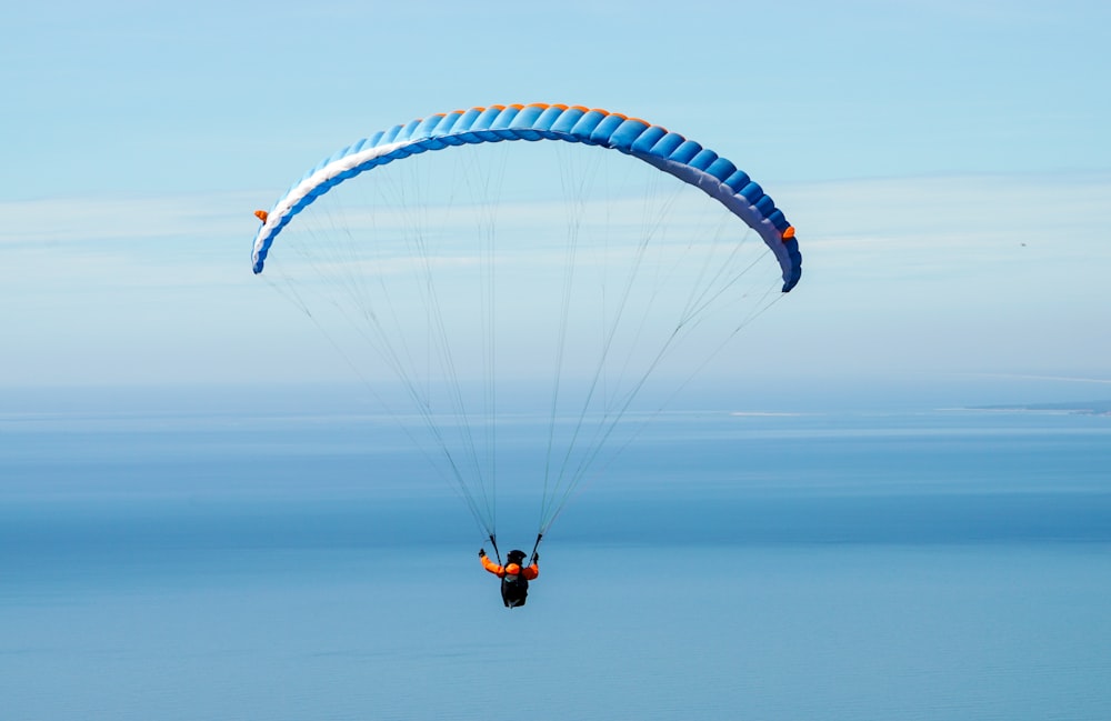 푸른 하늘 아래 낙하산을 타고 있는 사람