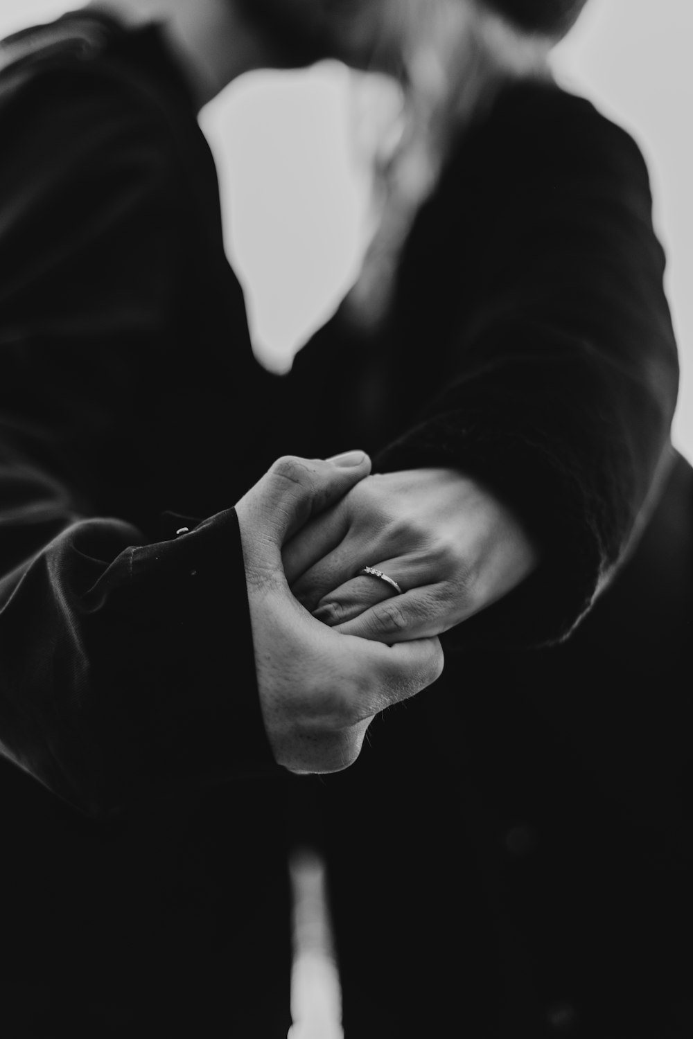 grayscale photo of man and woman kissing while holding hands