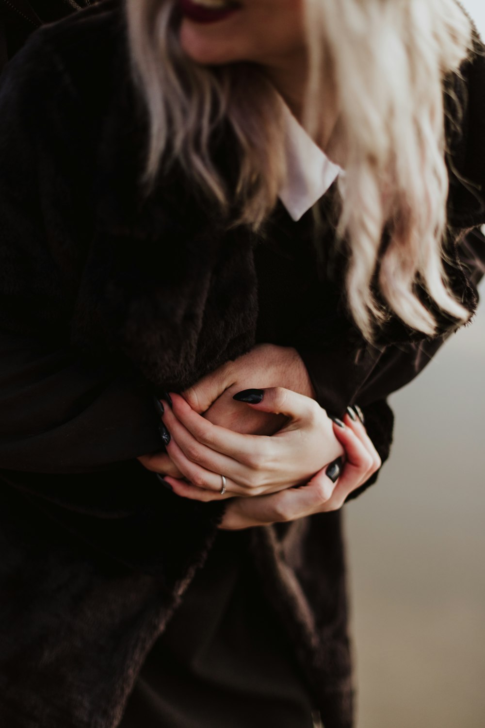 uma mulher com uma jaqueta preta segurando as mãos juntas