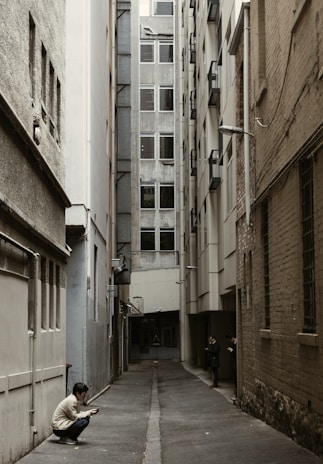 person in white top sitting beside wall