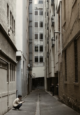 person in white top sitting beside wall