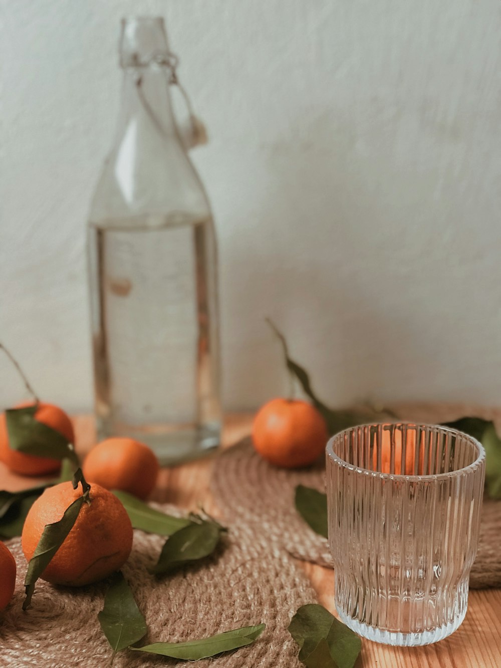orange fruits near empty clear drinking glass and glass bottle